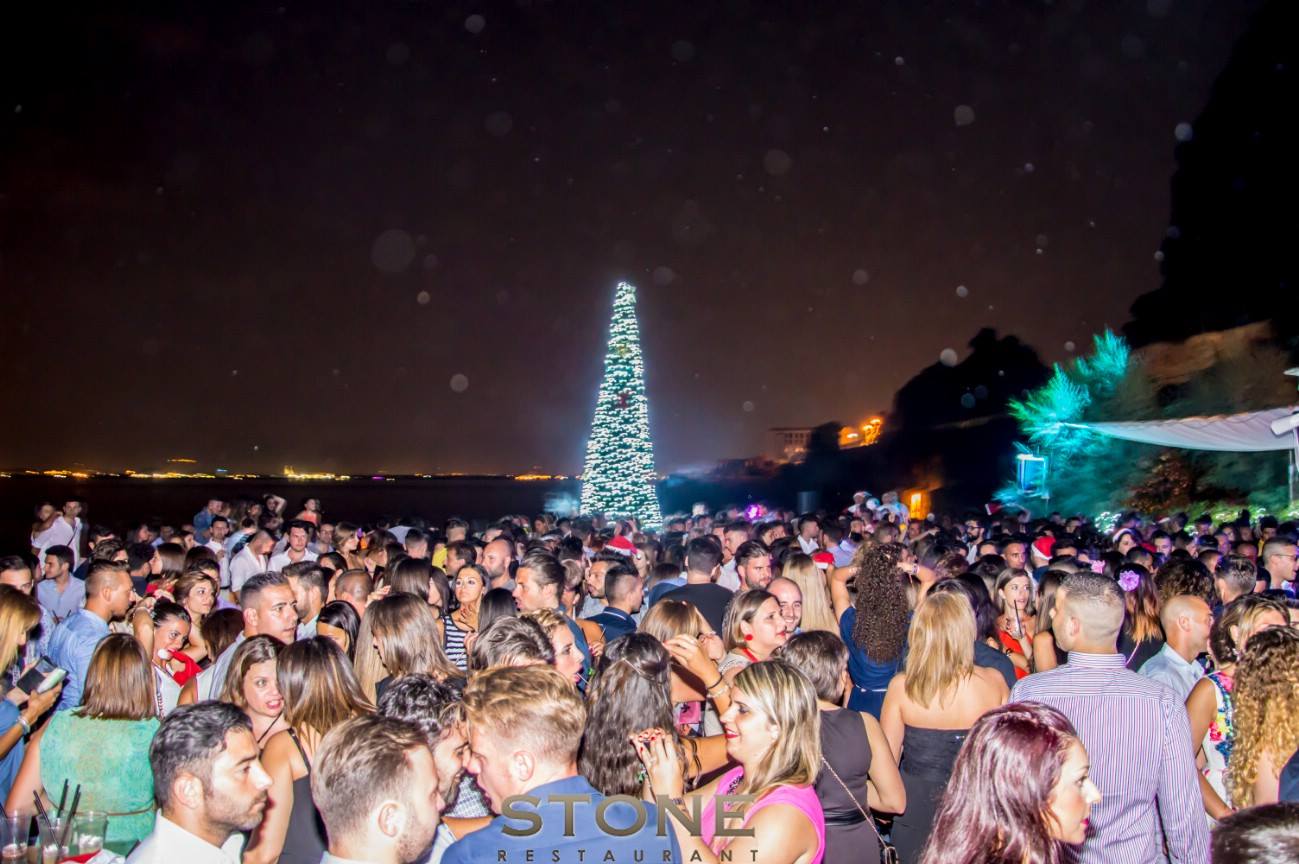 Folla festante durante un evento pubblico di capodanno estivo con un albero di Natale illuminato sullo sfondo